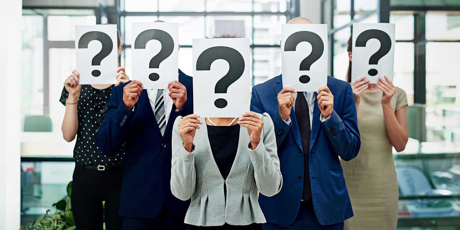 5 personnalités d'affaires, hommes et femmes, qui ont un carton blanc avec un point d'interrogation, se questionnant sur l'intelligence d'affaires en